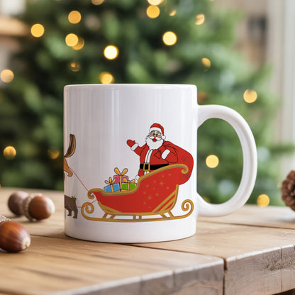 White mug with Santa Claus design on a wooden surface with a blurred Christmas tree in the background.