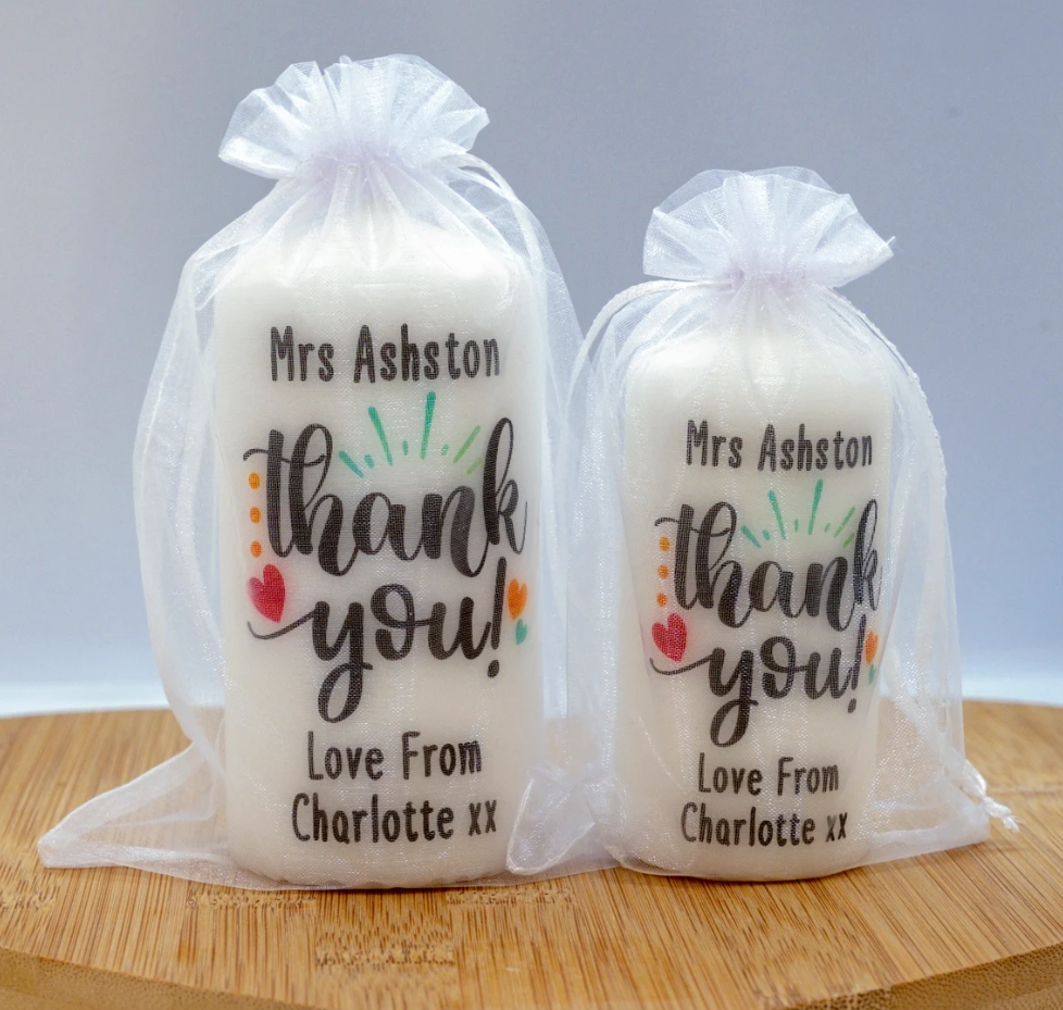 Two personalised white candles with printed 'Thank you' messages, customised with names and the expression 'Love from Charlotte.'.