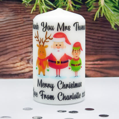 Personalized Christmas candle with Santa, reindeer, and elf design on a wooden surface.