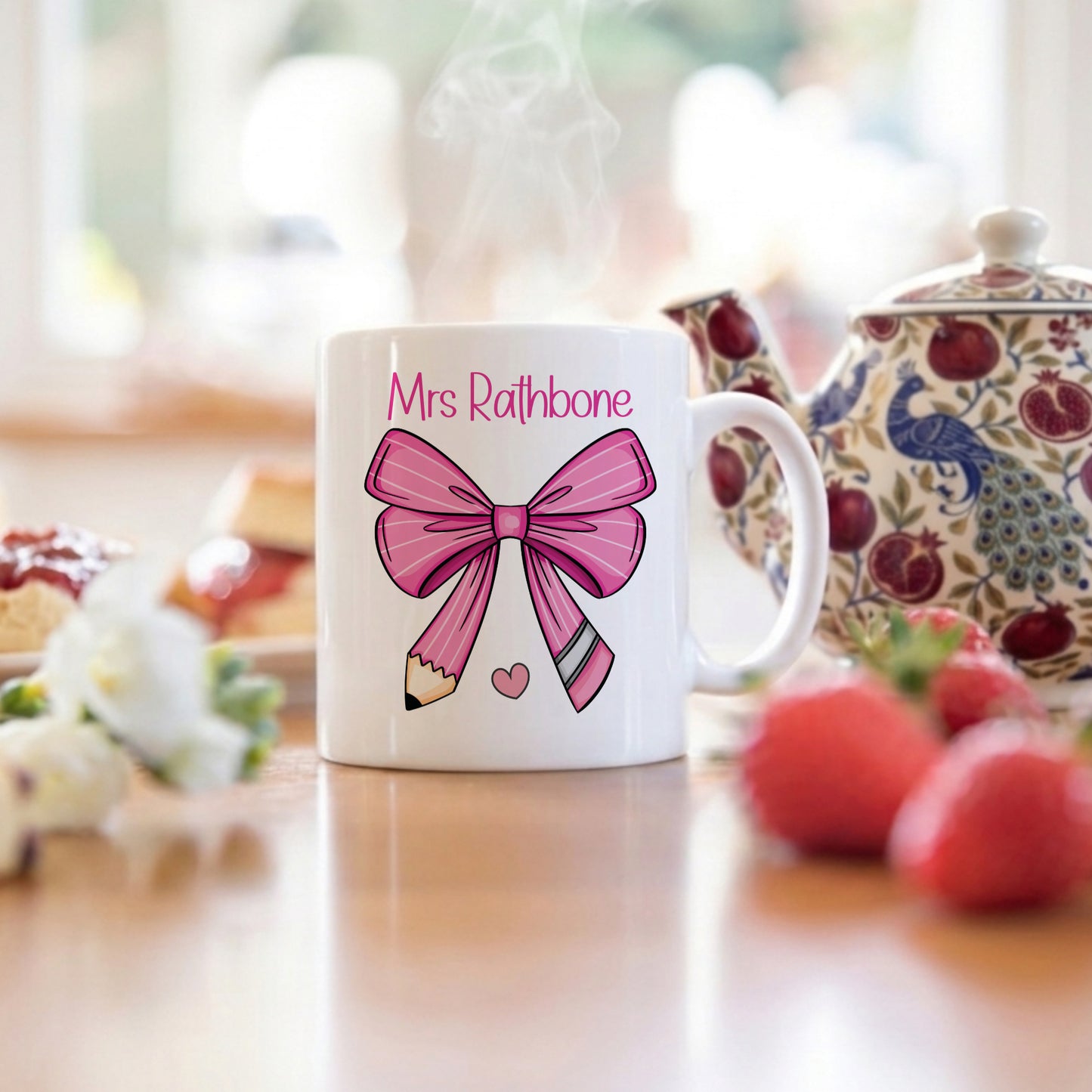 White mug with pink bow design and 'Mrs. Rathbone' text on a blurred background of a kitchen.