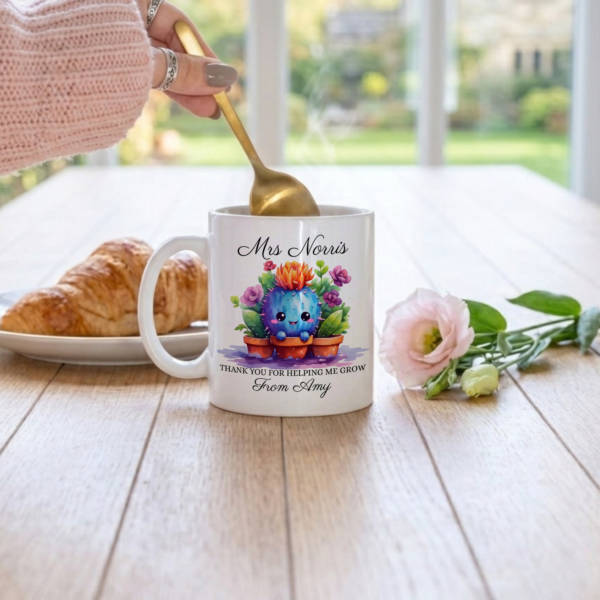 Personalised teacher thank you mug with cute watercolour cactus illustration in terracotta pots, personalised with 'Mrs Norris' and 'Thank You For Helping Me Grow From Amy' in script font, on a wooden table with a croissant and pink rose