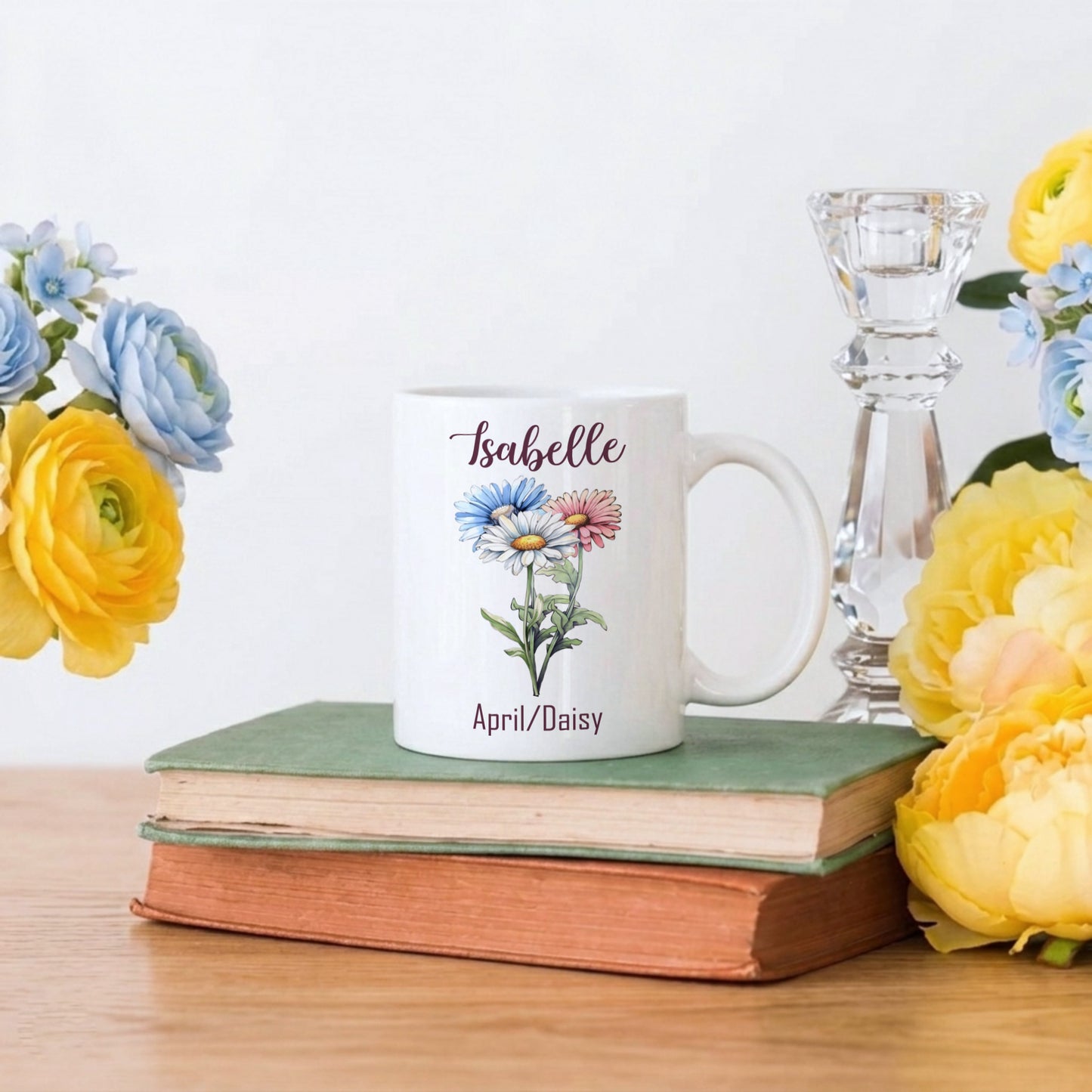 White mug with floral design and text on a stack of books with flowers around