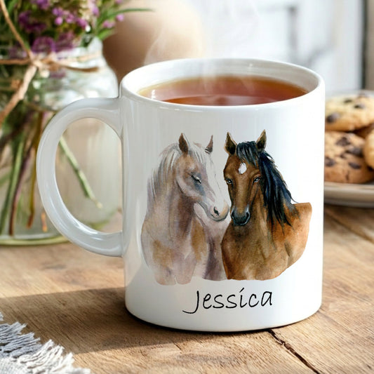 White mug with horse design and name 'Jessica' on a wooden table with tea and cookies.