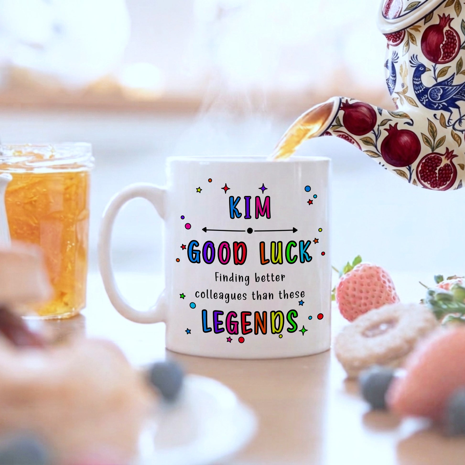 White mug with colourful text on a blurred background of food and drinks