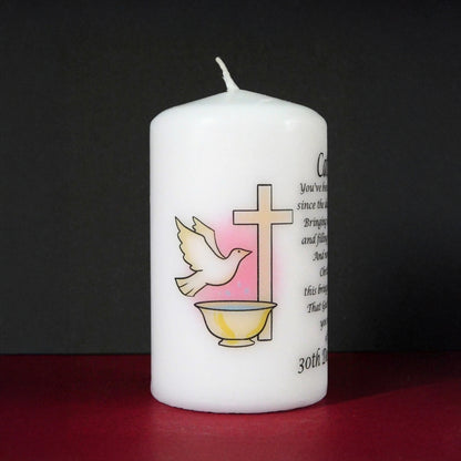 White candle with religious symbols and text on a dark background