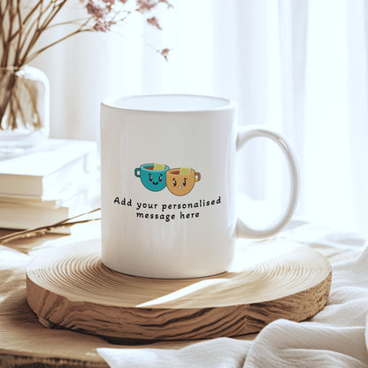 A white ceramic mug with a cute graphic of two smiling coffee cups and the text 'Add your personalised message here', displayed on a round wooden slice coaster in a bright, softly lit setting.