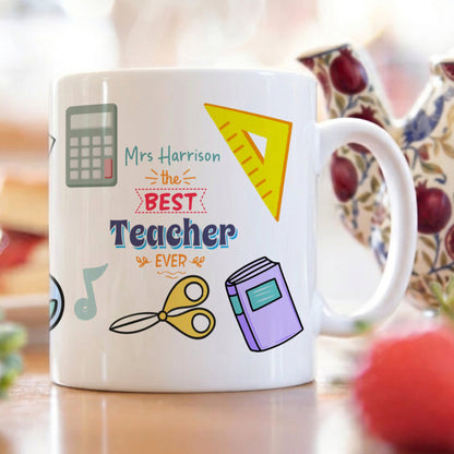 Mug with 'Best Teacher Ever' text and educational icons on a blurred background