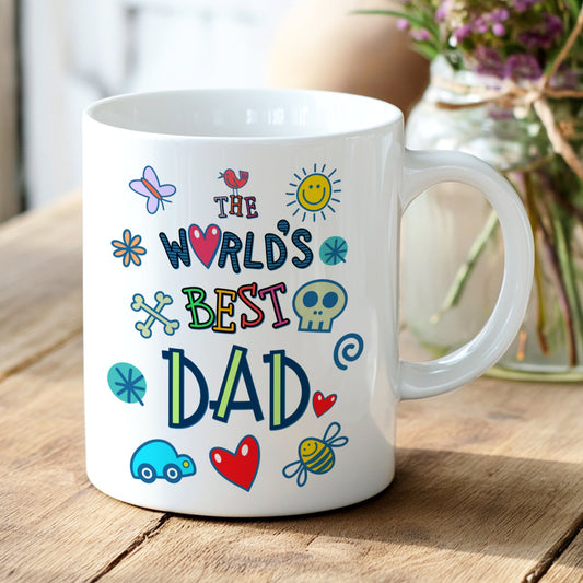 White mug with colorful text 'The World's Best Dad' on a wooden table with flowers in the background