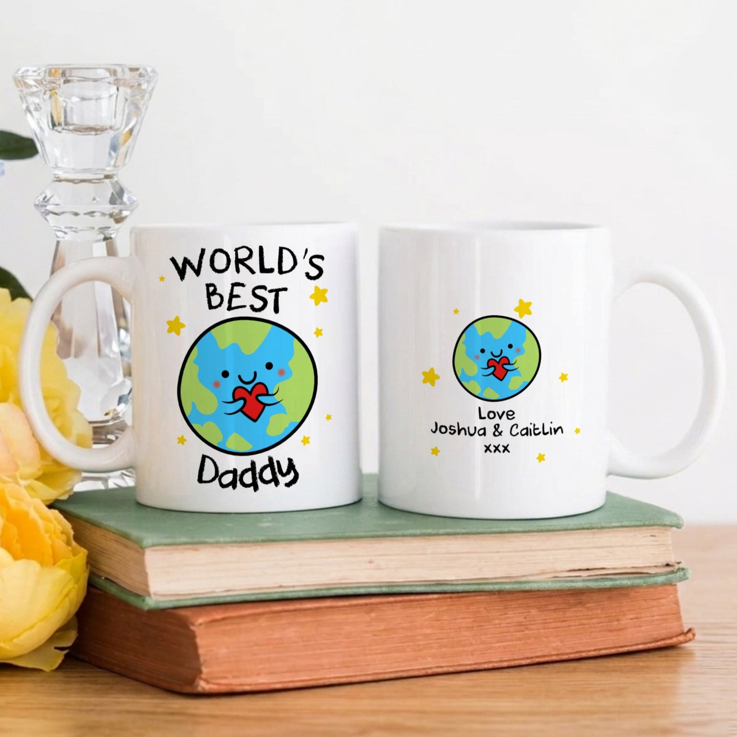 Two mugs with personalized designs on a wooden surface with flowers and a candle.