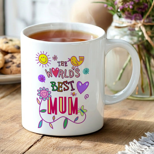 White mug with 'The World's Best Mum' text on a wooden table with tea and cookies.